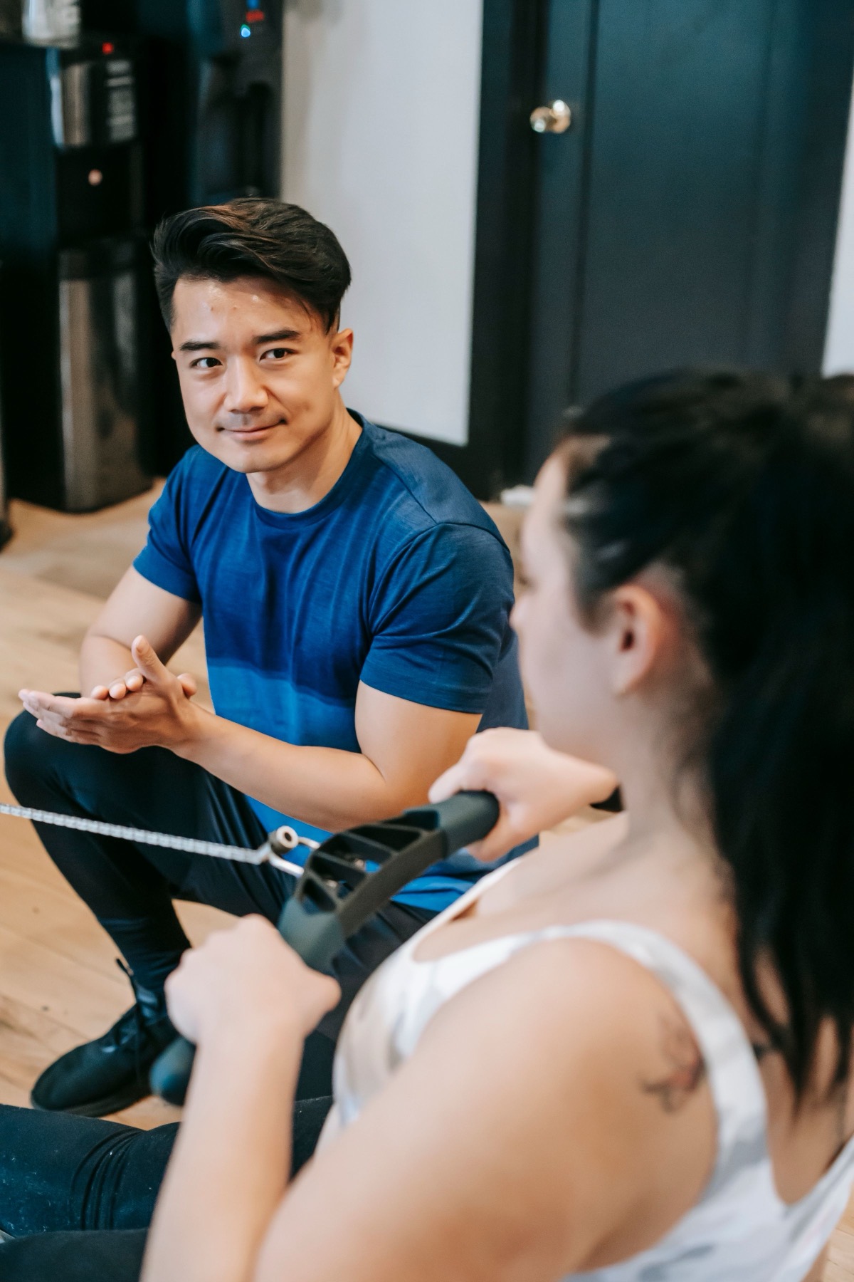 A trainer coaching a client through a pulling exercise in a gym