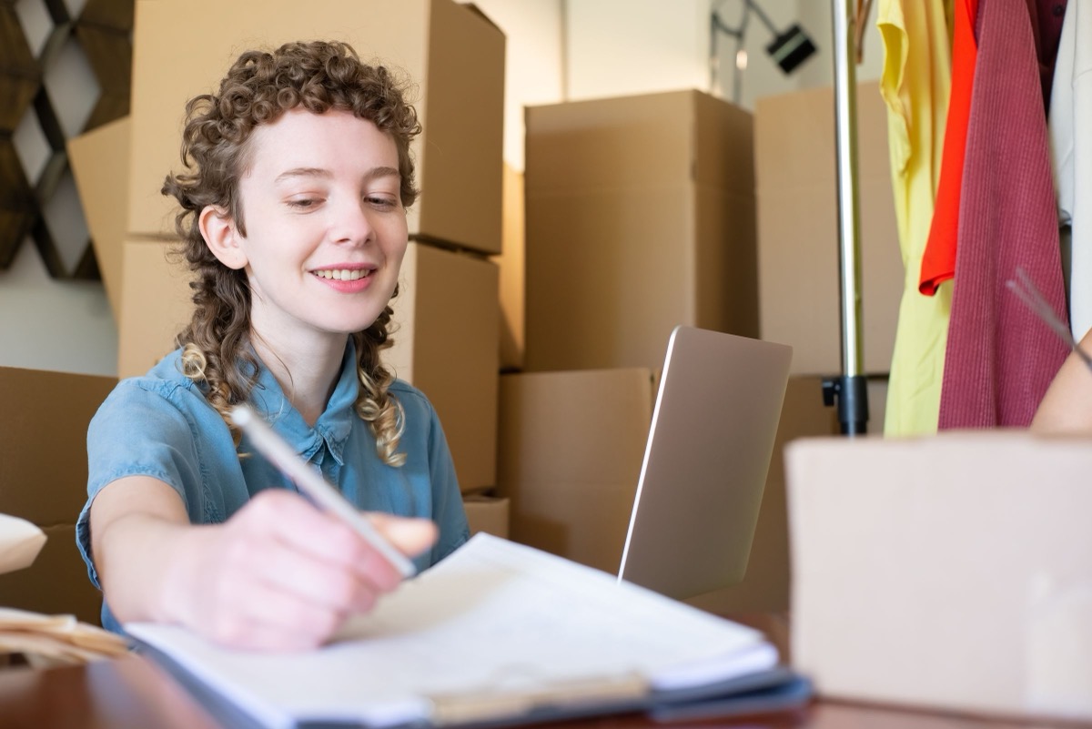 A small online seller writing up orders among parcels