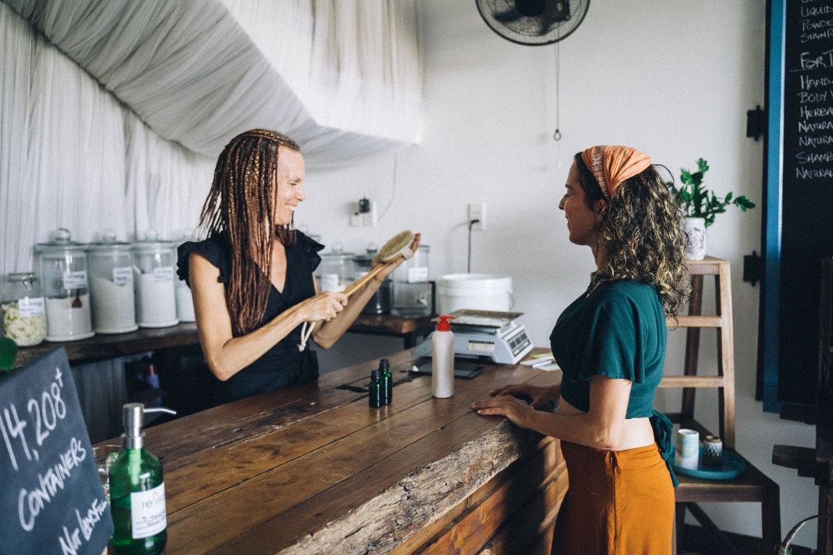A shop owner showing a product to a customer at the counter