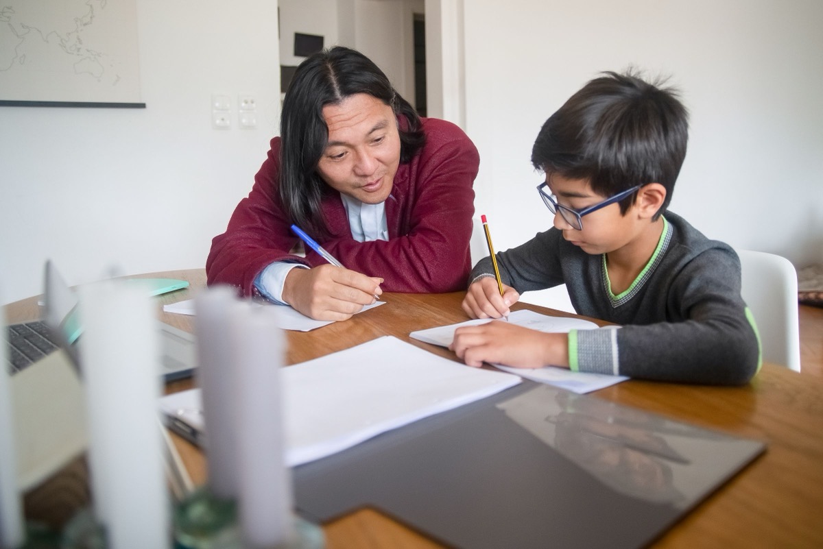 A tutor working through homework with a student at a table